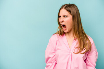Fototapeta premium Young caucasian woman isolated on blue background shouting very angry, rage concept, frustrated.