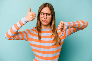 Young caucasian woman isolated on blue background showing thumbs up and thumbs down, difficult...