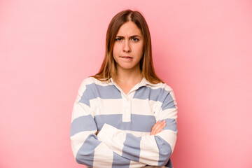 Young caucasian woman isolated on pink background frowning face in displeasure, keeps arms folded.