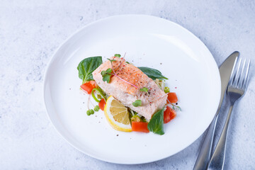 Trout (salmon) with vegetables, lemon and microgreens, cooked by the confit method. Traditional French dish. Step by step. Close-up.