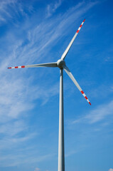 Windmill for electric power production against blue sky.
