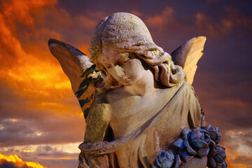 Death concept. Sad angel against dramatic sky. Fragment of an ancient statue.