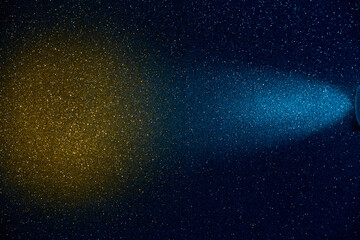 On a dark blue background in a finely grained light blue beam of light with a transition to a brown cloud of light
