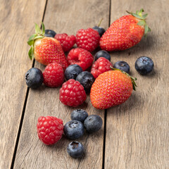 Raspberries, strawberries and blueberries over wooden table