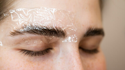 Caucasian woman on the procedure of permanent styling and coloring of eyebrows.
