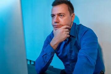 Millennial man sitting in office thinking about work project. Young businessman in blue shirt at...