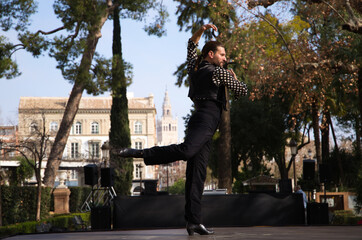 gypsy man with long hair dancing flamenco on an open air stage in a park in seville and he is doing...