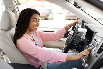 Smiling black woman driving new car in city