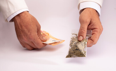 Pharmacy clerk hands over a bag of medical marijuana and takes the collection money with the other hand, on a white counter