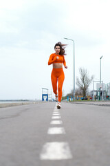 Young woman with the right body runs on the street. Women's model in sportswear, outdoor training