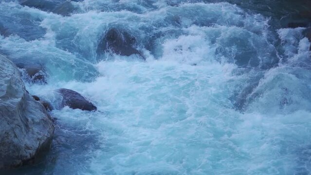 Slow motion shot of the Paravti River flowing in between mountains at Kasol in Himachal Pradesh, India. View of the Parvati river during the winter. Natural river in the mountains background.	