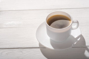 espresso coffee in a white classic cup on rustic wooden table. good morning, natural sunlight. copy space