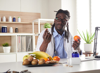 Afroamerican nutritionist looking at camera and showing healthy fruits in the consultation.