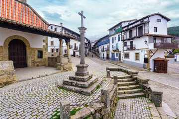 Fototapeta premium Village square with stone cross and mountain views in the village of Candelario, Salamanca, Spain.