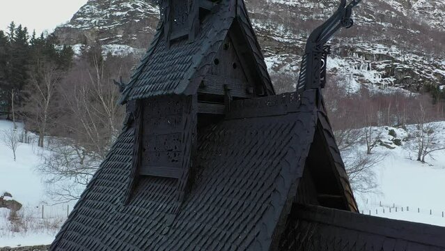 Borgund stave church closeup detail shot of tower with ornaments and dragon sculpture carvings in wood - Aerial rotating slowly close around top of historic building