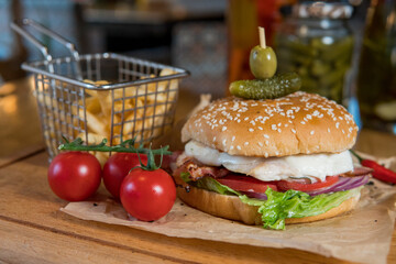 Burger with chicken breast, lettuce leaves, tomatoes, pickles and hot peppers