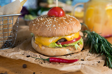 A burger with veal, cheese, lettuce leaves, tomatoes, pickles and hot peppers