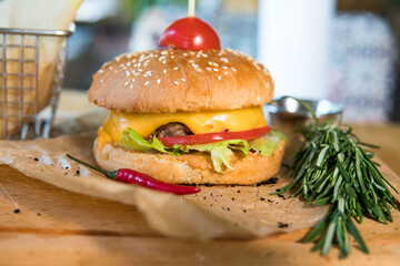 A burger with veal, cheese, lettuce leaves, tomatoes, pickles and hot peppers