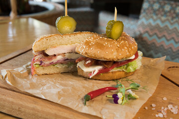 Burger with chicken breast, lettuce leaves, tomatoes, pickles and hot peppers