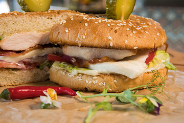 Burger with chicken breast, lettuce leaves, tomatoes, pickles and hot peppers