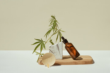 CBD oil in bottle and cannabis bush, hemp, wooden podium