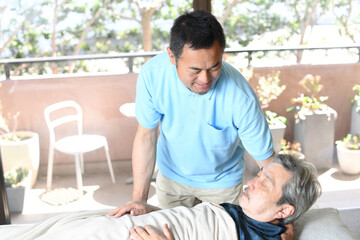 Fototapeta premium 高齢者をベッドで介助する男性介護士 