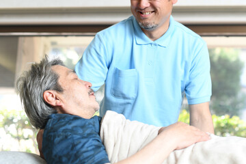 高齢者をベッドで介助する男性介護士
