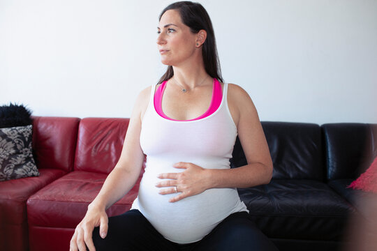 Serene pregnant woman in tank top touching baby bump