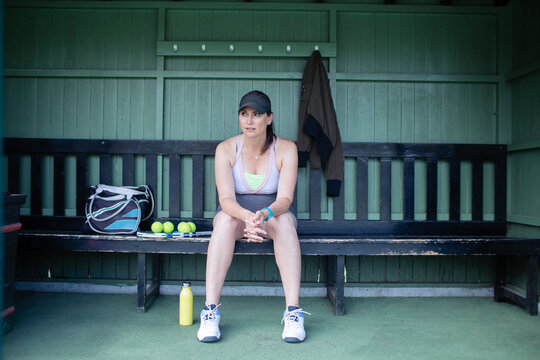 Pregnant woman resting on bench at tennis court