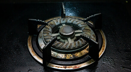 Close up view of modern dirty stove with food leftover. Unclean and wet gas kitchen cooktop with greasy spots, old fat stains, fry spots and oil splatters. Unsanitary conditions, a mess in the house.