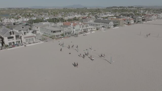 Slow motion aerial pan down shot of volleyball game on the beach in Costa Mesa, California.