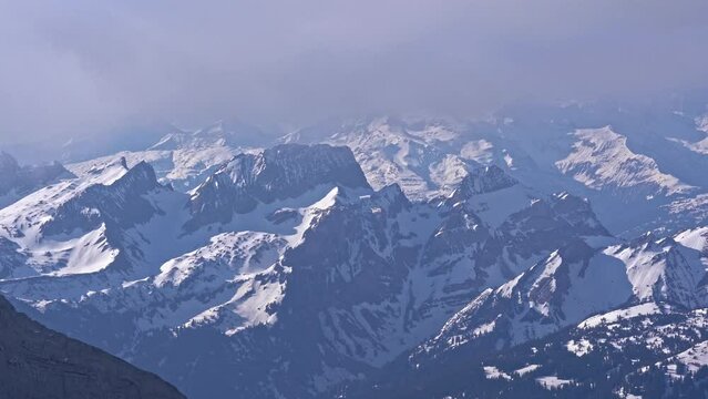Snow capped mountains with beautiful panoramic view over the Swiss Alps seen from Säntis peak on a blue cloudy spring morning. Movie shot April 19th, 2022, Säntis, Switzerland.