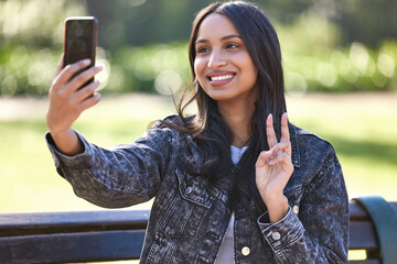 Content and comfortable. Shot of a beautiful young student using her phone while sitting outside.