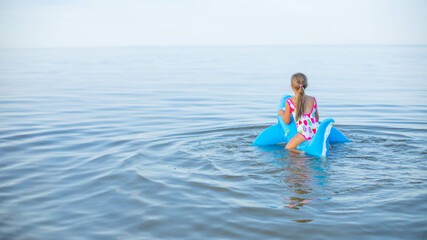  Happy girl swimming on an inflatable shark toy in the sea