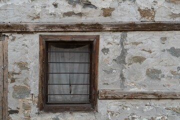 Old wooden window with curtains.Stone wall