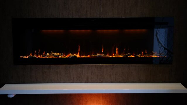 view on electric fireplace with artificial sparkling flame, decor for the interior, orange flame on crystals with orange backlighting.