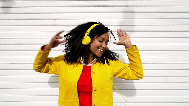 Young multiethnic happy woman dancing outdoor while listening music with the headphones