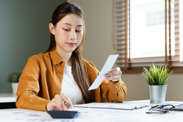 Asian young employee business woman calculate tax income and expenses, bills, credit card for...