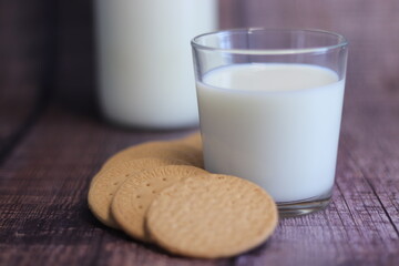 Vaso de leche con galletas con una botella de leche al fondo