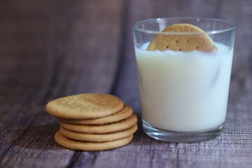 Vaso de leche con galleta dentro y al lado un montoncito de galletas