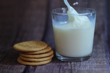 Vaso de leche con galleta cayendo dentro