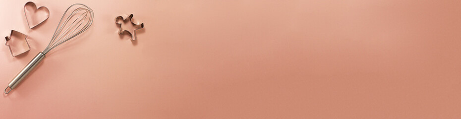 Banner of steel whisk house men and heart shaped cutter on the left flat lay top view. Confectionery cooking concept with copy space on bright pink paper background