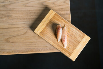 raw sea bass nigiri photographed from above on wooden cutting board, Japanese cuisine