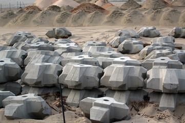 Plac budowy materiały budowlane betonowe bloczki i stalowe pręty zwały piasku.	
