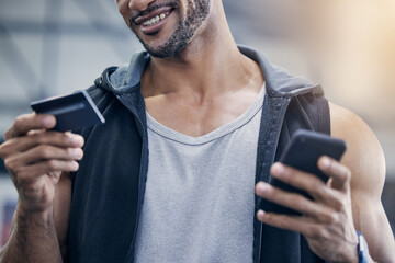 A gym membership is worth the investment for me. Closeup shot of a muscular young man using a cellphone and credit card in a gym.