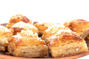 Sweet baklava classic on a clay dish, macro, isolated on a white background.
