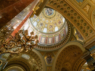 Fototapeta na wymiar Budapest basilica dome cupola ceiling in upward view with marble arches and golden candelabra