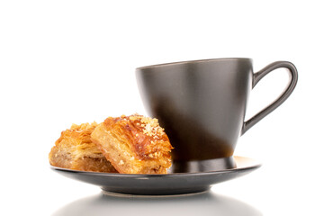 Sweet baklava classic with a cup on a ceramic saucer, macro, isolated on a white background.