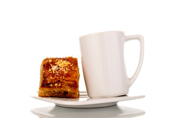 Sweet baklava classic with a cup on a ceramic saucer, macro, isolated on a white background.