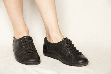 Black sneakers on the feet of a girl on a white carpet, shoes